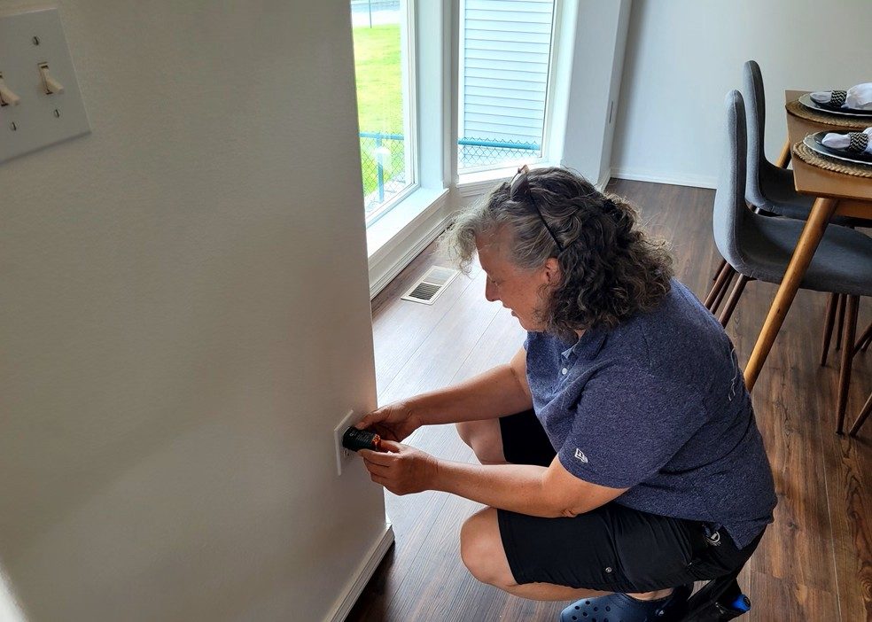 Tina testing an electrical outlet during an inspection