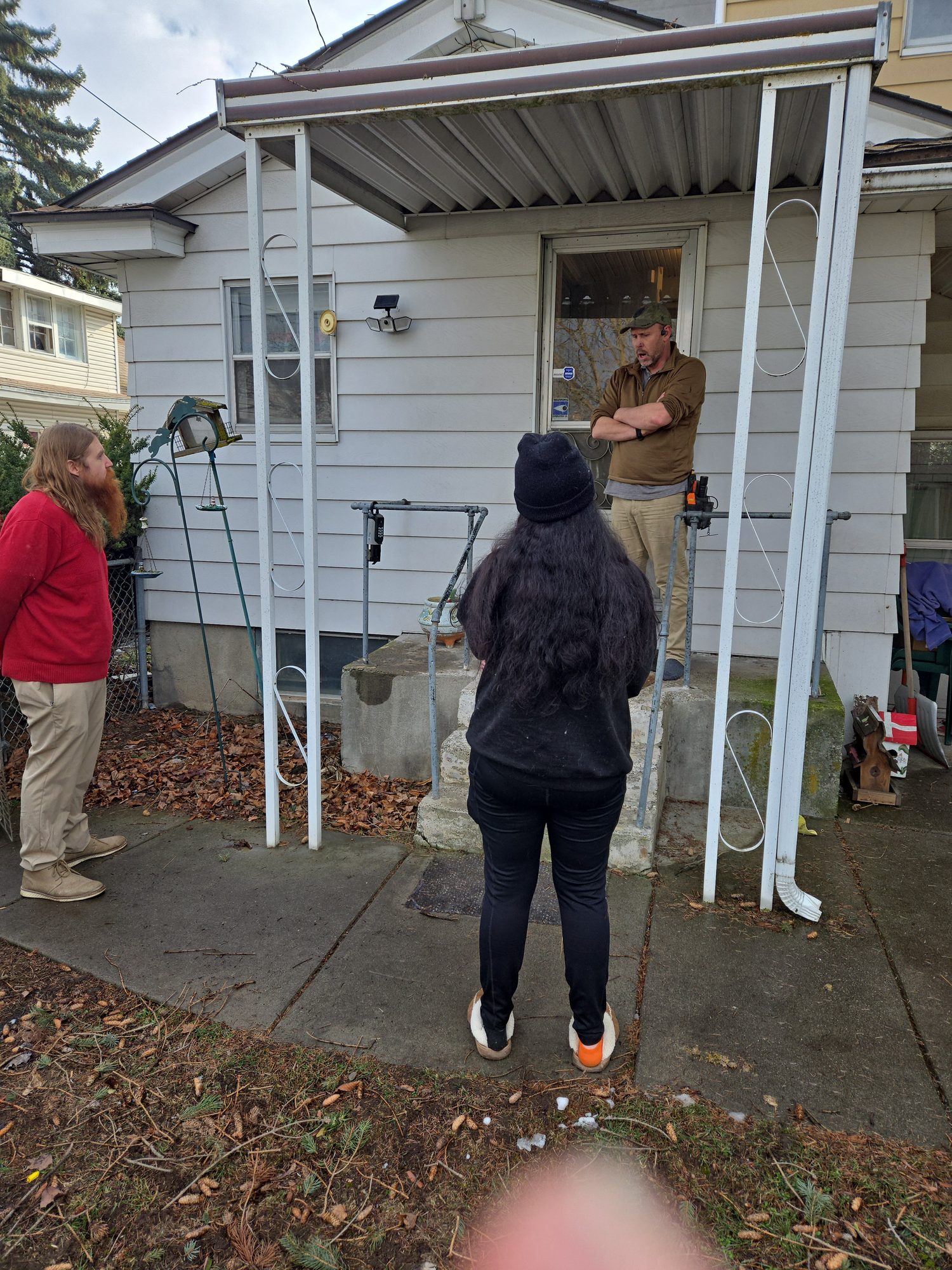 Inspector reviewing findings with an agent and buyers outside a home