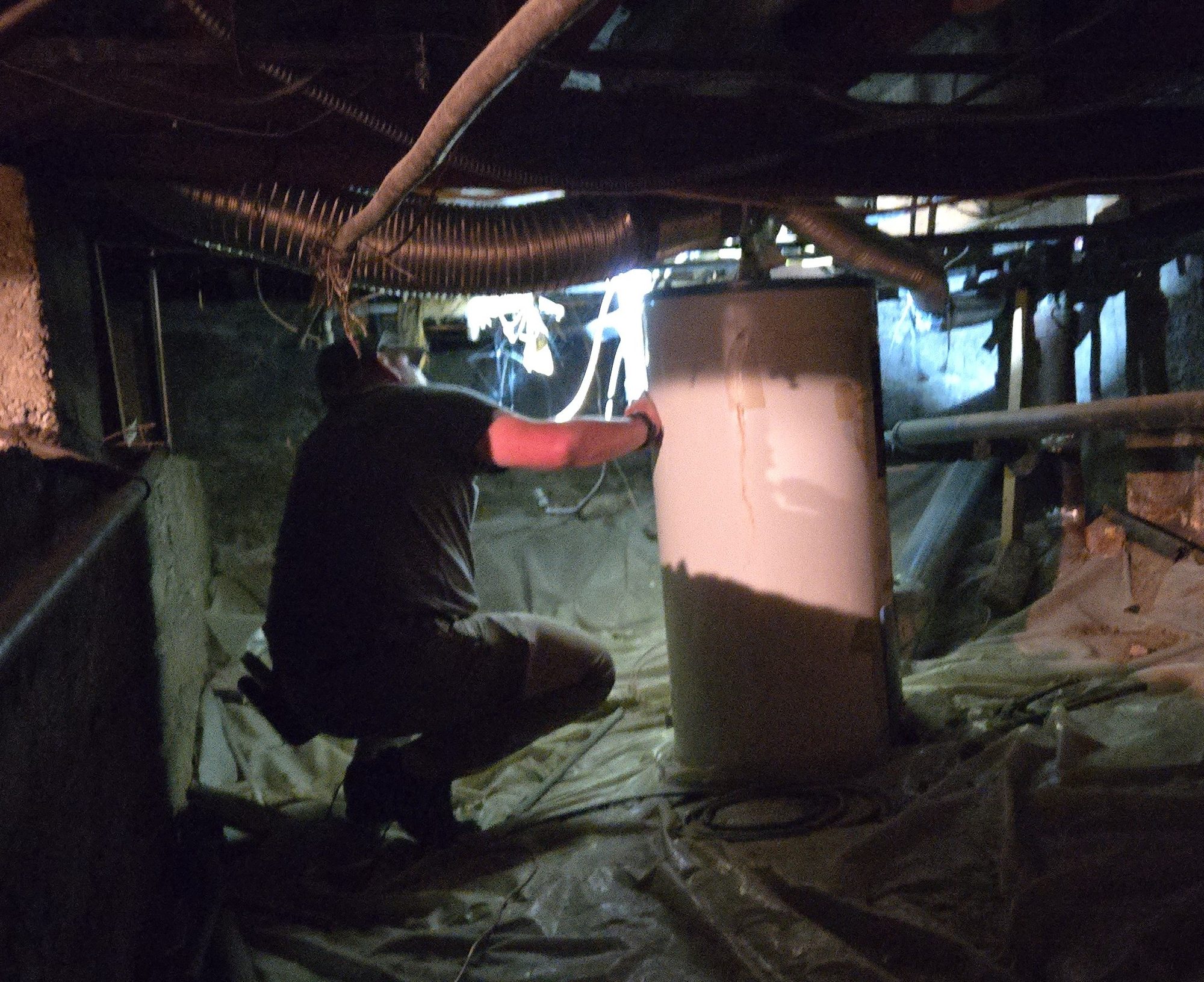 Inspector examining a water heater in a crawlspace